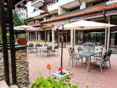 an outdoor patio with tables and chairs and umbrellas at Orbilux - Cozy Studio in Bansko by Flat Mаnager in Bansko