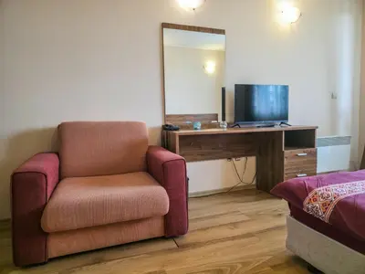 a room with a chair and a desk with a television at Orbilux - Cozy Studio in Bansko by Flat Mаnager in Bansko