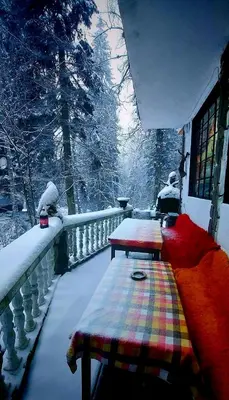 a balcony covered in snow with two benches on a railing at Villa Byala Luna - Guest House in Bistriza