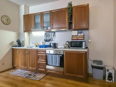 a kitchen with wooden cabinets and a stove top oven at Charming 1BD Flat at Edelweiss Inn, Bansko by Flat Mаnager in Bansko