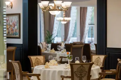 a dining room with tables and chairs and a chandelier at Mantar Spa Hotel in Marikostinovo