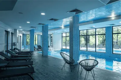 a swimming pool with chairs and tables and windows at SIBIYA Hotel in Ognyanovo