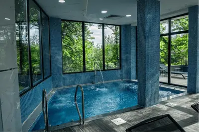 a bathroom with a large blue tub with windows at SIBIYA Hotel in Ognyanovo