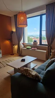 a living room with a couch and a table and a large window at Boho Style in Samokov