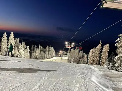 a person riding a ski lift on a snow covered slope at Hrebet House in Borovets