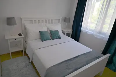 a bedroom with a white bed with blue pillows at Hrebet House in Borovets