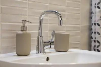 a bathroom sink with a soap dispenser and a faucet at Mall of Sofia - UrbanLux Ampla 2BDR FREE Parking in Sofia