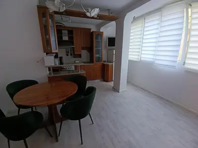 a kitchen with a wooden table and green chairs at АПАРТАМЕНТ ДВЕ СТАИ ДО МЕТРОСТАНЦИЯ ВАРДАР Apartment In West Park near Subway in Sofia