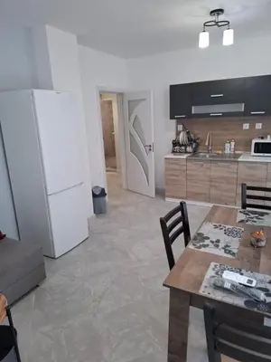 a kitchen with a table and a white refrigerator at Apartment Active Sport in Pazardzhik