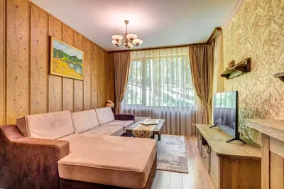 a living room with a couch and a tv at Апартамент Борчето Forest Glade- Pamporovo in Pamporovo