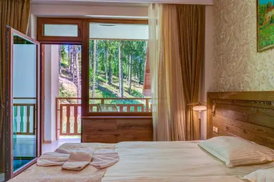 a bedroom with a bed and a large window at Апартамент Борчето Forest Glade- Pamporovo in Pamporovo