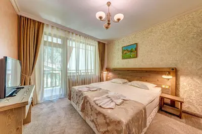 a bedroom with a large bed and a television at Апартамент Борчето Forest Glade- Pamporovo in Pamporovo