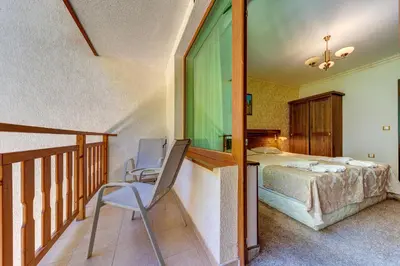 a bedroom with a bed and a chair on a balcony at Апартамент Борчето Forest Glade- Pamporovo in Pamporovo