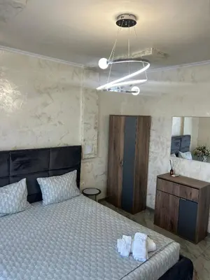 a bedroom with a bed and a dresser and a light at Платинум 8 in Plovdiv