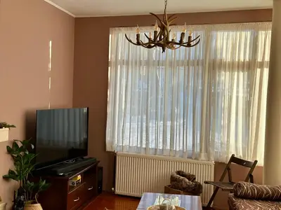 a living room with a television and a chandelier at Chalet Hamars - Highland Haven in Razlog