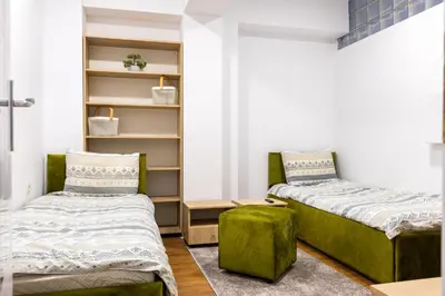 a bedroom with two beds and a green ottoman at Mont Blanc Apartment in Bansko