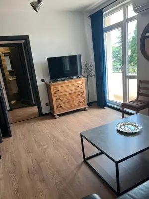 a living room with a flat screen tv on a wooden dresser at Cozy apartment, by Paradise Mall in Sofia