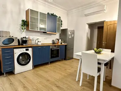 a kitchen with blue cabinets and a table and a washing machine at Spacious 1BR Apartment in Central Sofia, Next to University in Sofia
