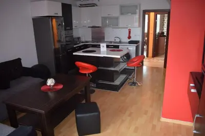 a kitchen with a stove and a table with red chairs at Pirin 7 in Pazardzhik