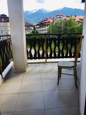 a chair on a balcony with a view of mountains at Beautiful two bedroom 4th floor apartment in Elegant Luxe Hotel with pool, sauna, gym and steam room in Bansko