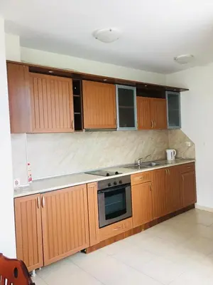 a kitchen with wooden cabinets and a stove top oven at Beautiful two bedroom 4th floor apartment in Elegant Luxe Hotel with pool, sauna, gym and steam room in Bansko