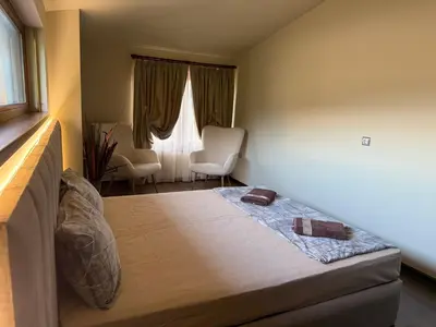 a bedroom with a bed with a chair and a window at Къщата на тати in Garmen