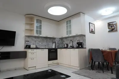a kitchen with white cabinets and a tv and a table at Top Central Apartment 2 in Sofia
