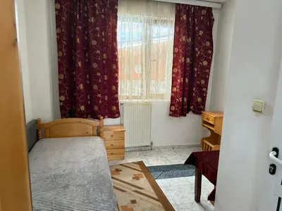 a bedroom with a bed and a window with curtains at Къща за гости Гаджо Gadjo in Bansko