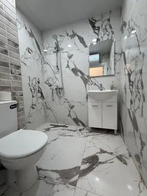 a bathroom with a toilet and a marble wall at Stay Point One Bedroom Apartment Including Underground Parking Place in Sofia