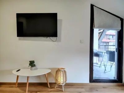 a living room with a table and a tv on a wall at White Peak 2rooms ap in Bansko
