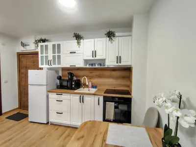 a kitchen with white cabinets and a wooden table at White Peak 2rooms ap in Bansko
