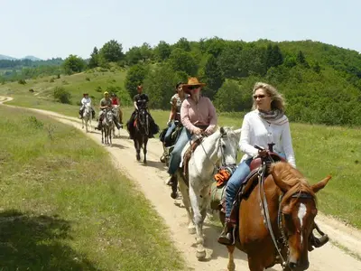 a group of people riding horses down a dirt road at Chamkoria Forest View & Spa Apartment in Borovets