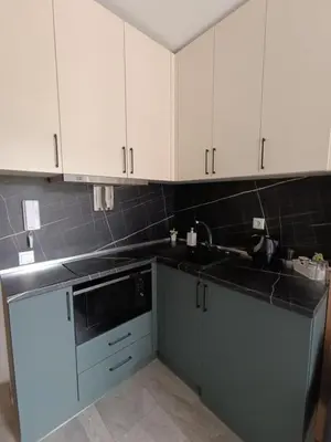 a kitchen with white cabinets and a black counter top at Green Apart Residence Including Parking Place in Sofia