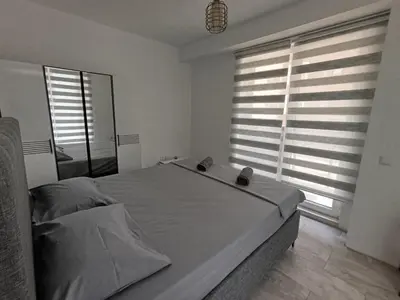 a bedroom with a large bed and two windows at Green Apart Residence Including Parking Place in Sofia