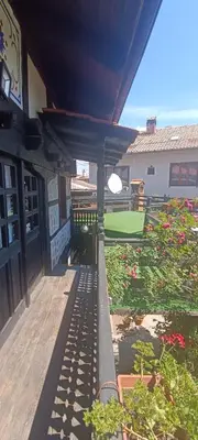 a porch of a building with a yard with flowers at Къща за гости- Шале Мила in Bansko