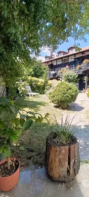 a garden with a tree stump and a bench at Къща за гости- Шале Мила in Bansko