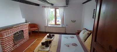 a living room with a brick fireplace and a table at Къща за гости- Шале Мила in Bansko
