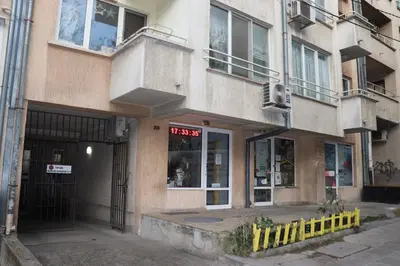 a building with a store with a yellow fence in front of it at Комфортен апартамент, безплатно гараж! in Sofia