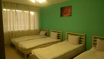 three beds in a room with a green wall at Стаи за гости Деметра in Sofia