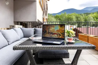 a laptop on a table on a couch on a balcony at Incredible 2BDR with Veranda and House-like Feel in Bansko