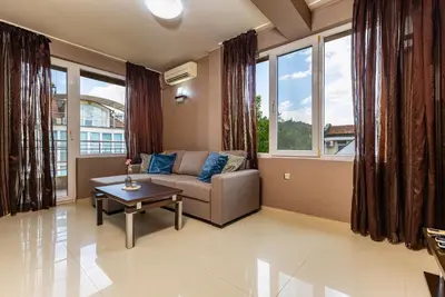 a living room with a couch and a table and windows at Modern 2BD - 14 min to Medical University by Flat Manager in Plovdiv