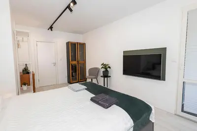a white bedroom with a large bed and a flat screen tv at D-home in Sofia