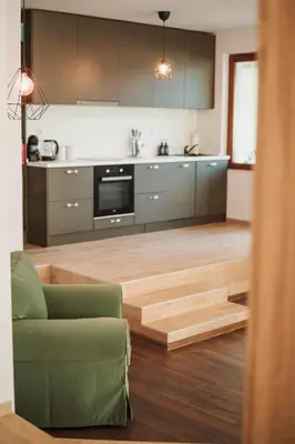 a kitchen with wooden flooring and a green couch in a room at Pavlina Guest House in Tsŭrvishte