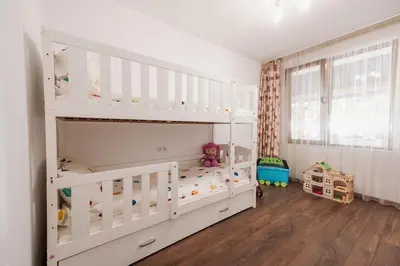 a white bunk bed in a room with wooden floors at Pavlina Guest House in Tsŭrvishte