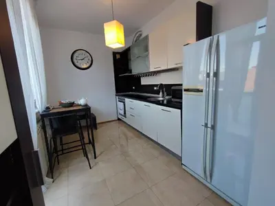 a kitchen with a refrigerator and a table with a clock at Simply The Best - Vitosha blvd in Sofia