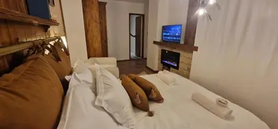 a white bed with pillows and a television in a room at Boutique Apartment Katerina in Bansko