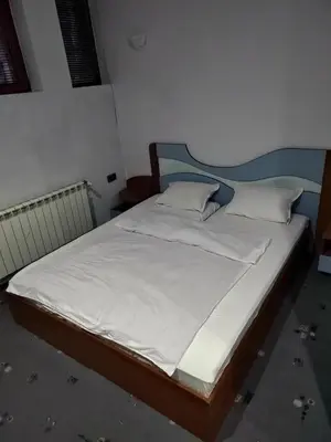 a bed with white sheets and pillows in a room at Семеен хотел МАКСИМ in Teteven