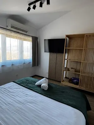 a bedroom with a large bed and a flat screen tv at Уютни планински апартаменти с басейн в комплекс Алпин Лодж in Bansko
