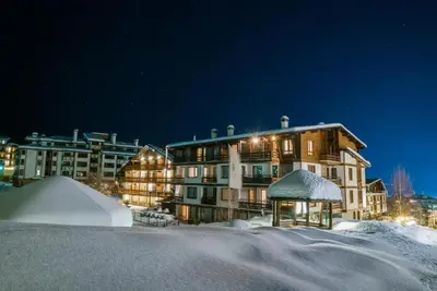 a large building in the snow at night at Green Life Cozy Studio Bansko in Bansko