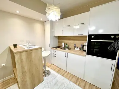 a kitchen with white cabinets and a black appliance at Winter Palace Vitosha View Studio in Sofia